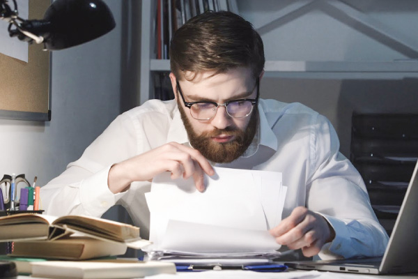 Ensimetri tarjoaa maksutonta neuvontaa aloittaville yrityksille. Kuvassa mies selaa papereita työpöydän ääressä.